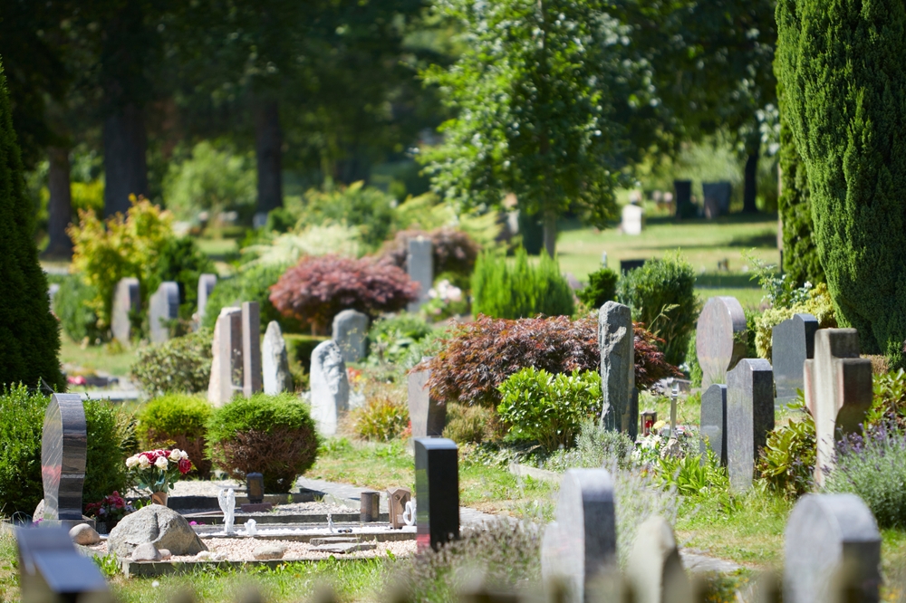 cemetery tombstones surrounded by shrubs and trees from landscaping