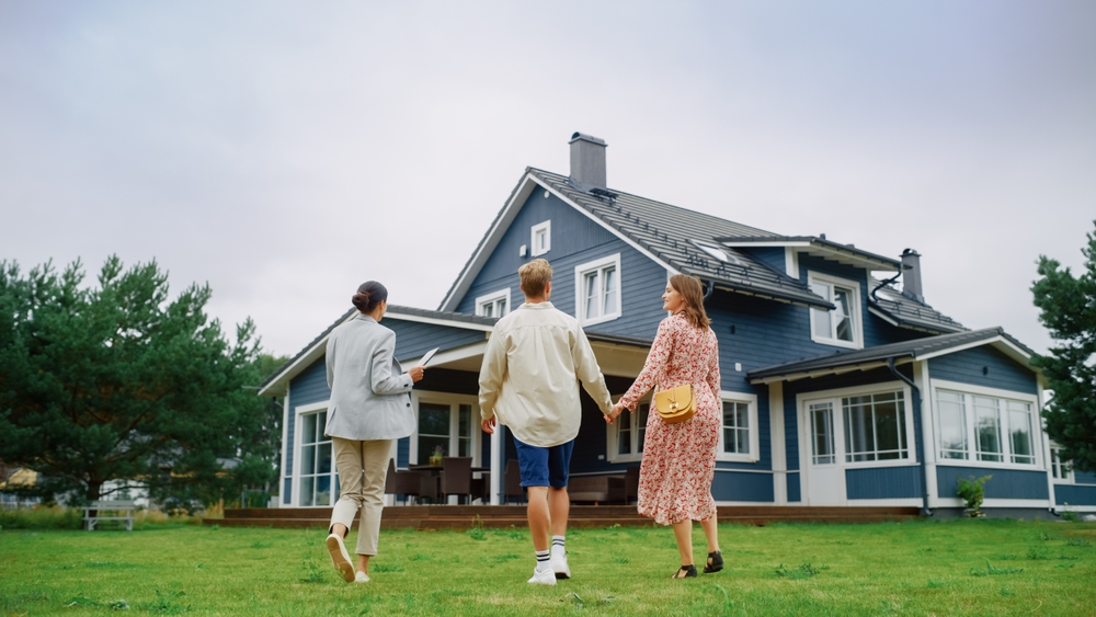 realtor walking on grass selling house to couple