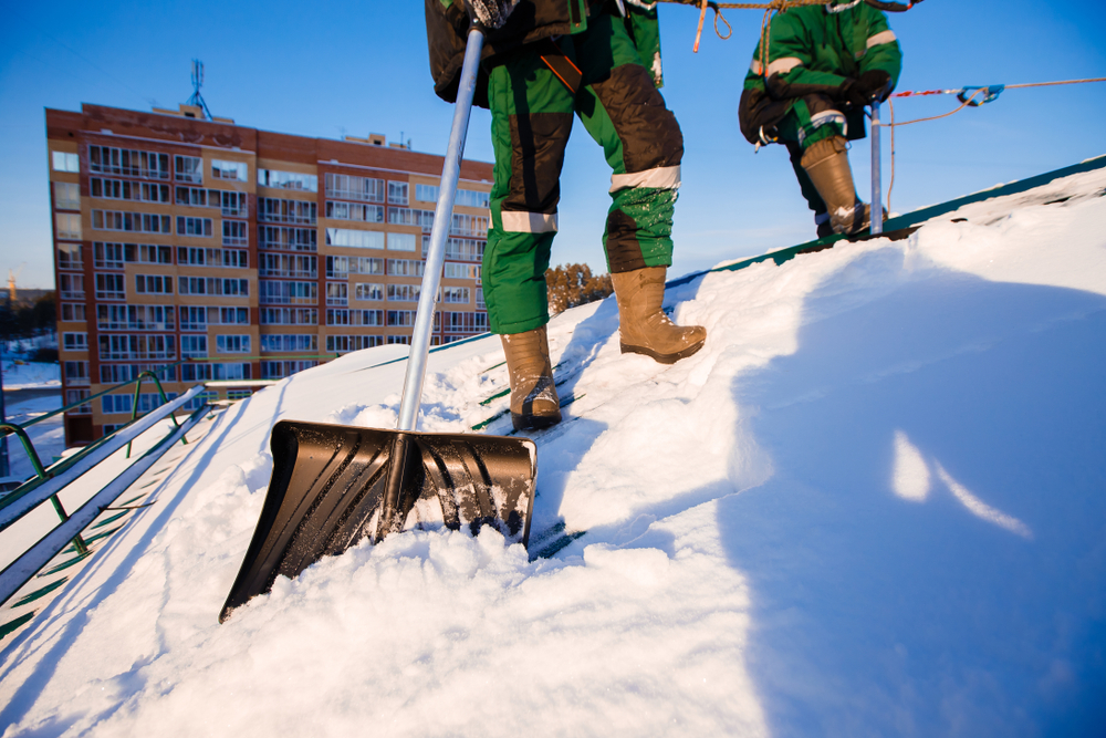 Crew cleaning building roof from snow