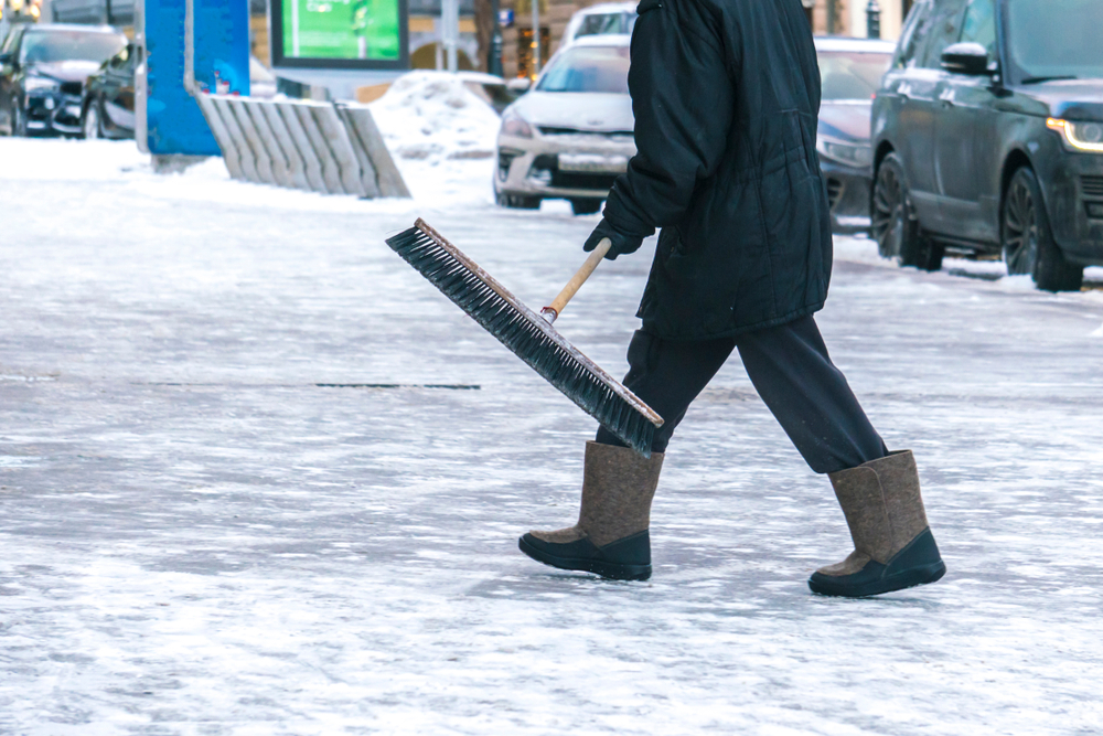 Worker carrying brush for cleaning snow