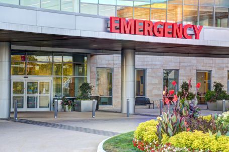 smiling nurse helping elderly walk in landscaped hospital garden